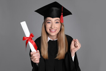 Happy student with diploma on grey background