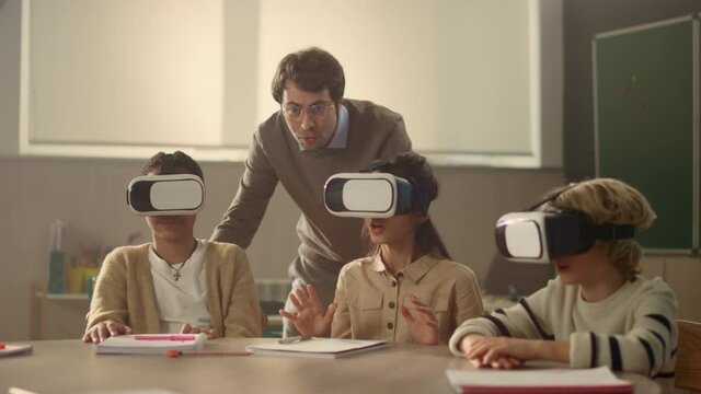 Young schoolteacher explaining students how to use modern gadgets in education