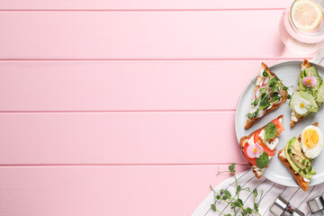 Different tasty sandwiches served on pink wooden table, flat lay. Space for text