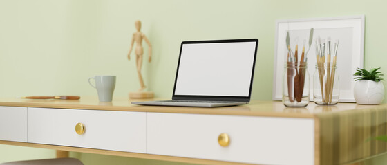 Computer laptop with mock-up screen on the desk with paint tools and decorations, 3D rendering