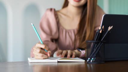 Cropped shot of female hand writing on notebook, planning her schedule