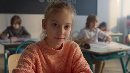 Serious student posing at camera in classroom. Cheerful girl sitting at desk  - Powered by Adobe