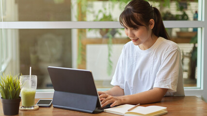 Portrait of female student doing assignment with digital tablet and stationery in home garden