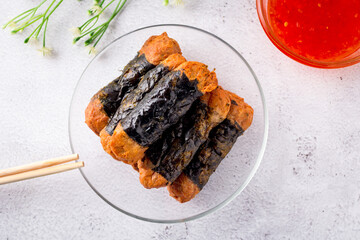 Top view of Seaweed Chicken Roll are stacked on a glass plate with chopsticks and sweet chilli sauces.