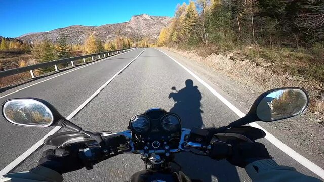 Driver riding motorcycle on the empty asphalt road in Mountains