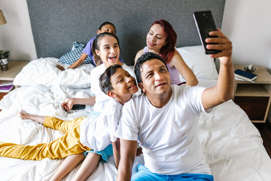 Mexican family and girl with cerebral palsy on bed at Home taking a photo selfie with phone in disability concept in Latin America