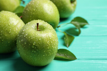 Fresh ripe green apples with water drops on turquoise wooden table, closeup
