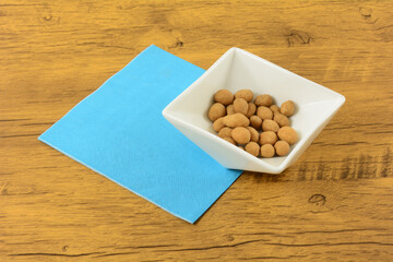 Coconut cream flavored peanuts in white nut bowl with blue napkin