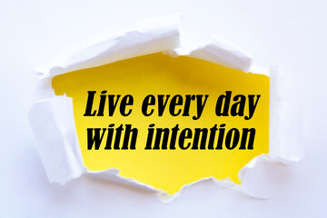 Live every day with intention. Words written under torn paper. Motivation concept text.