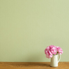 Vase of pink carnation flowers on wooden table. khaki green background