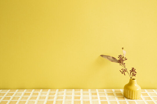 Vase Of Dry Flowers On Beige Ceramic Mosaic Tile Table. Yellow Wall Background. Home Interior