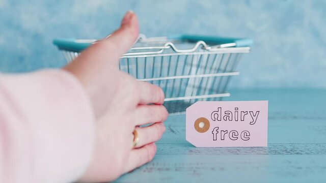 dairy vs dairy-free product tags with shopping basket and hand removing the dairy option, plant-based food or allergies and nutritional choices