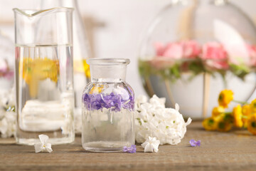 Fototapeta na wymiar Laboratory glassware with flowers on wooden table. Extracting essential oil for perfumery and cosmetics