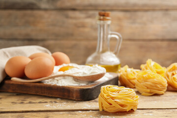 Raw noodles and ingredients on wooden table, space for text