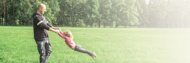 Father playing with his cute little daughter on the field. Concept of friendly family. Great family vacation.