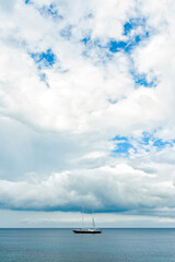 Fototapeta premium Stunning view of a luxury sailboat sailing on a beautiful calm sea during a dramatic, cloudy day.Sardinia, Italy. Recreational pursuit, copy space.