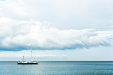 Fototapeta premium Stunning view of a luxury sailboat sailing on a beautiful calm sea during a dramatic, cloudy day.Sardinia, Italy. Recreational pursuit, copy space.