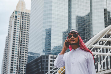 Fototapeta premium Islamic man using smartphones app organize schedule agenda focus on hands holding smartphone muslim modern uae city. Arab men wear hijab and muslim formal dress sending text sms online lifestyle
