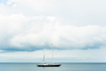 Stunning view of a luxury sailboat sailing on a beautiful calm sea during a dramatic, cloudy day.Sardinia, Italy. Recreational pursuit, copy space.