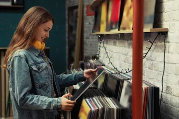 Wall murals Music store Young woman with vinyl record in store