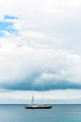 Fototapeta premium Stunning view of a luxury sailboat sailing on a beautiful calm sea during a dramatic, cloudy day.Sardinia, Italy. Recreational pursuit, copy space.