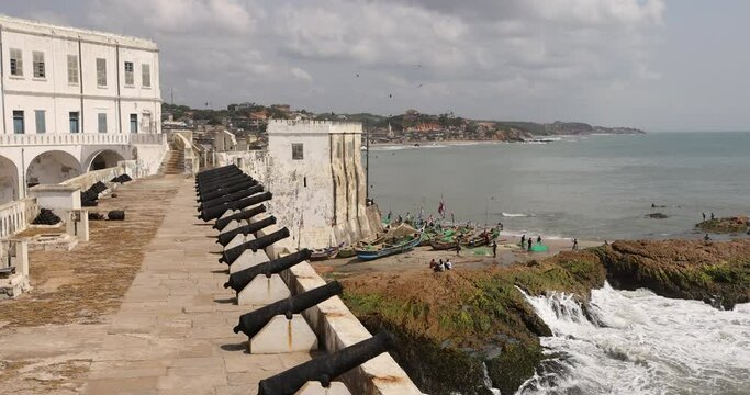 Cape Coast castle canon wall fishing boats Ghana 4K. Slave castles or fort on the Gold Coast of West Africa by European traders. Millions of African slaves passed through here.