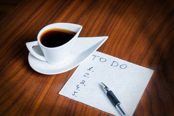 blank to-do list on white napkin and coffee cup on wooden table, personal day planning concept
