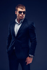 Obraz premium Fashion bearded young serious man in sunglasses, luxury suit with one hand in pocket
