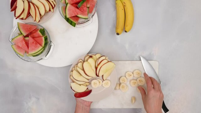 Woman hands serving fruit salad, close up video, flat lay. Fruit salad, healthy delicious desert recipe