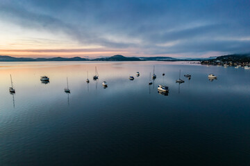 Obraz na płótnie Canvas Sunrise waterscape with boats, light cloud and fog