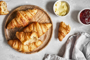 Fresh sweet croissants with butter and strawberry jam for breakfast.