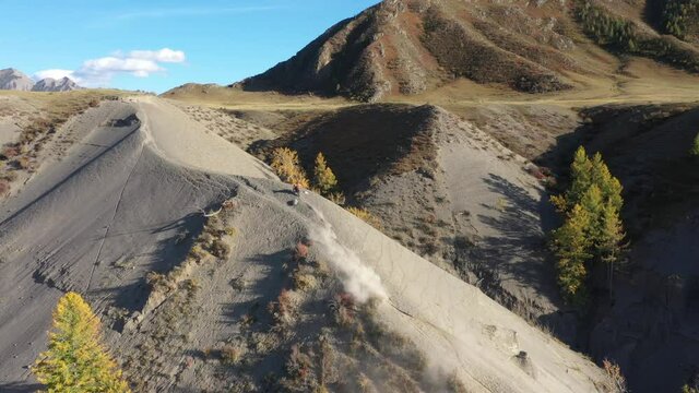 Rider climbing sand mountain on  off-road cross motorcycle, aerial drone video