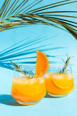 Close-up lemonade, orange cocktail, refreshing summer drink with ice in a glass with a sprig of...