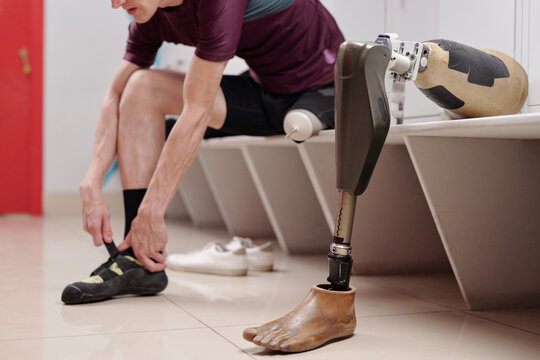 Robotic leg on bench against disabled man putting on protective footwear