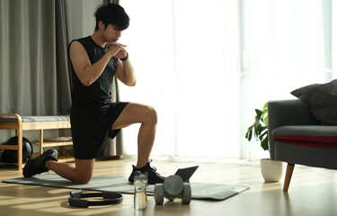 Young male in sportswear workout in living room.