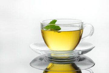 Yellow herbal tea in glass cup with leaf. Close-up  cup of freshly brewed hot tea.