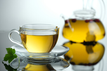 Yellow herbal tea in glass cup with leaf. Close-up  cup of freshly brewed hot tea.