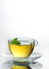 Yellow herbal tea in glass cup with leaf. Close-up  cup of freshly brewed hot tea.