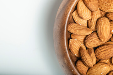 Background of big raw peeled almonds in a wooden bowl. Tip view.