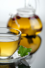 Yellow herbal tea in glass cup with leaf. Close-up  cup of freshly brewed hot tea.