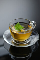 Yellow herbal tea in glass cup with leaf. Close-up  cup of freshly brewed hot tea.