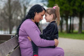 cute girl and her mom touching with foreheads, at evening park outdoors.Summer evening,closeup shot.