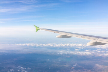 View from the airplane window at a beautiful blue sunrise and the airplane wing above the clouds.