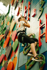 young child girl on indoor climbing wall, bouldering