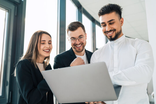 Cheerful company workers look into a laptop and laugh
