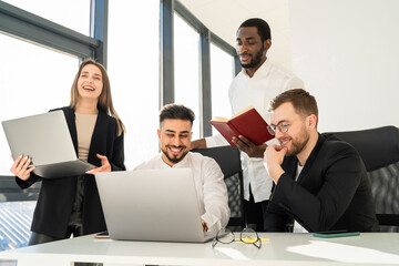 Cheerful business team working at laptops on new project