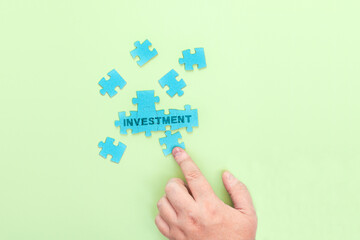 Businessman connecting puzzle pieces with the word Investment
