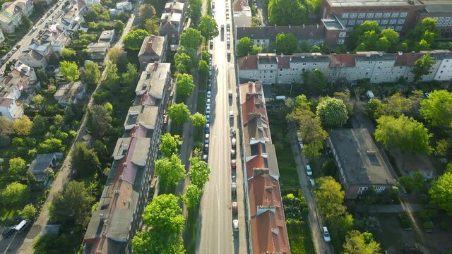 Aerial View of Residential District and Line of Cars Parked in the Street Along the Buildings in Gdansk on Sunset, tilt-up revealing shot
