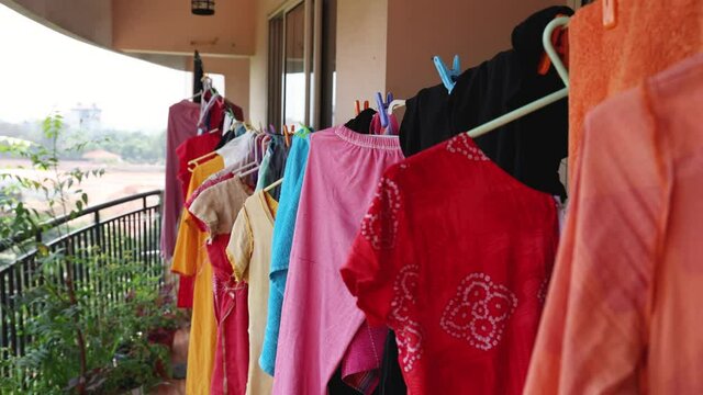 Hanging clothes on washing line for drying in balcony of apartment building a summer day Kerala India Sri Lanka 4K slow motion video. wash stain dirty clothing use detergent , drying dress in sun.