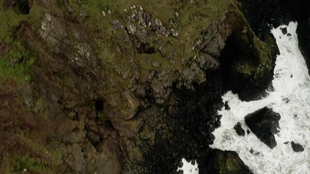 Drone overhead of the ocean waves crashing along the coast tilt up  to the Cornwall setting using in the filming of Poldark